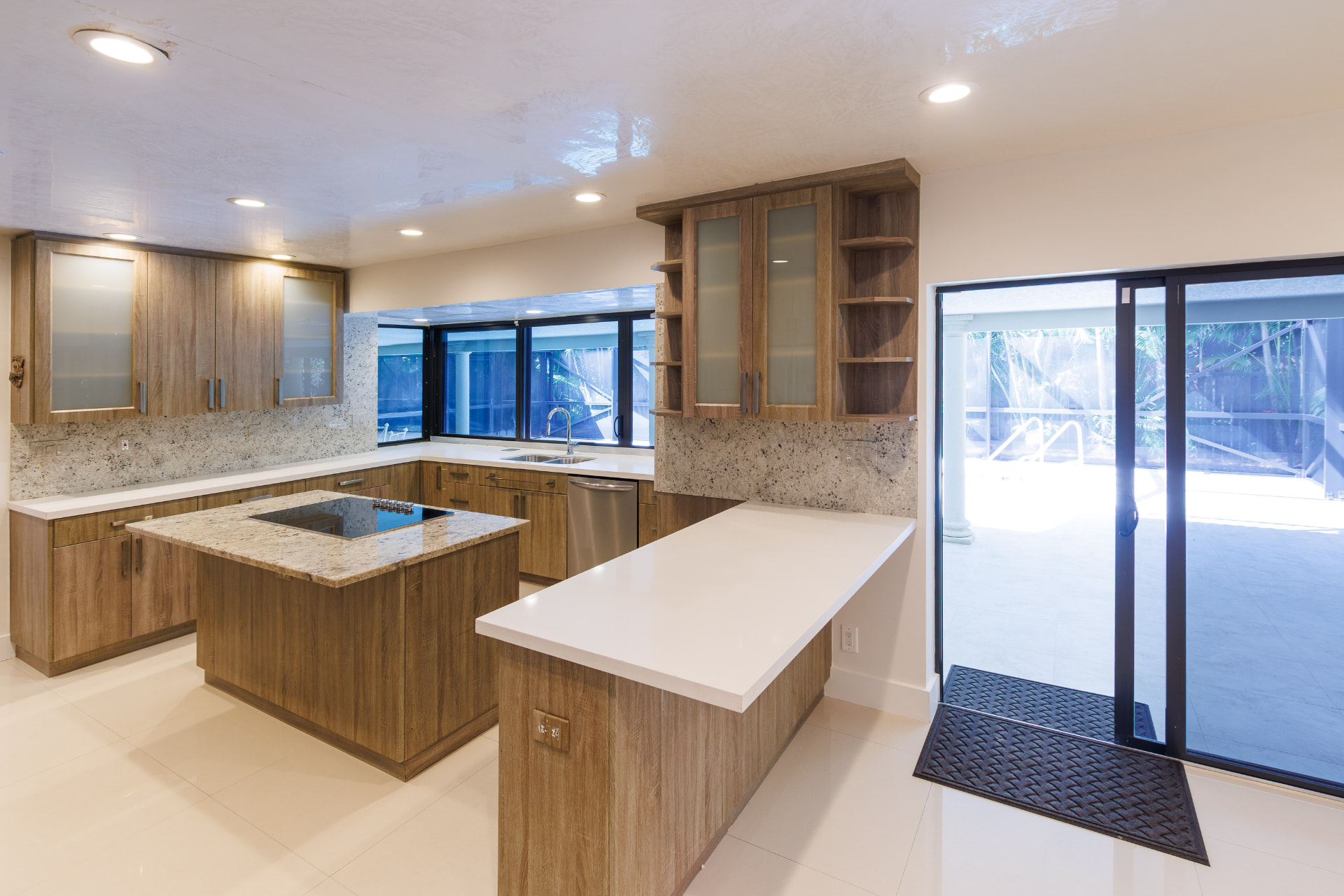 Kitchen with granite island, induction cooktop and pool views