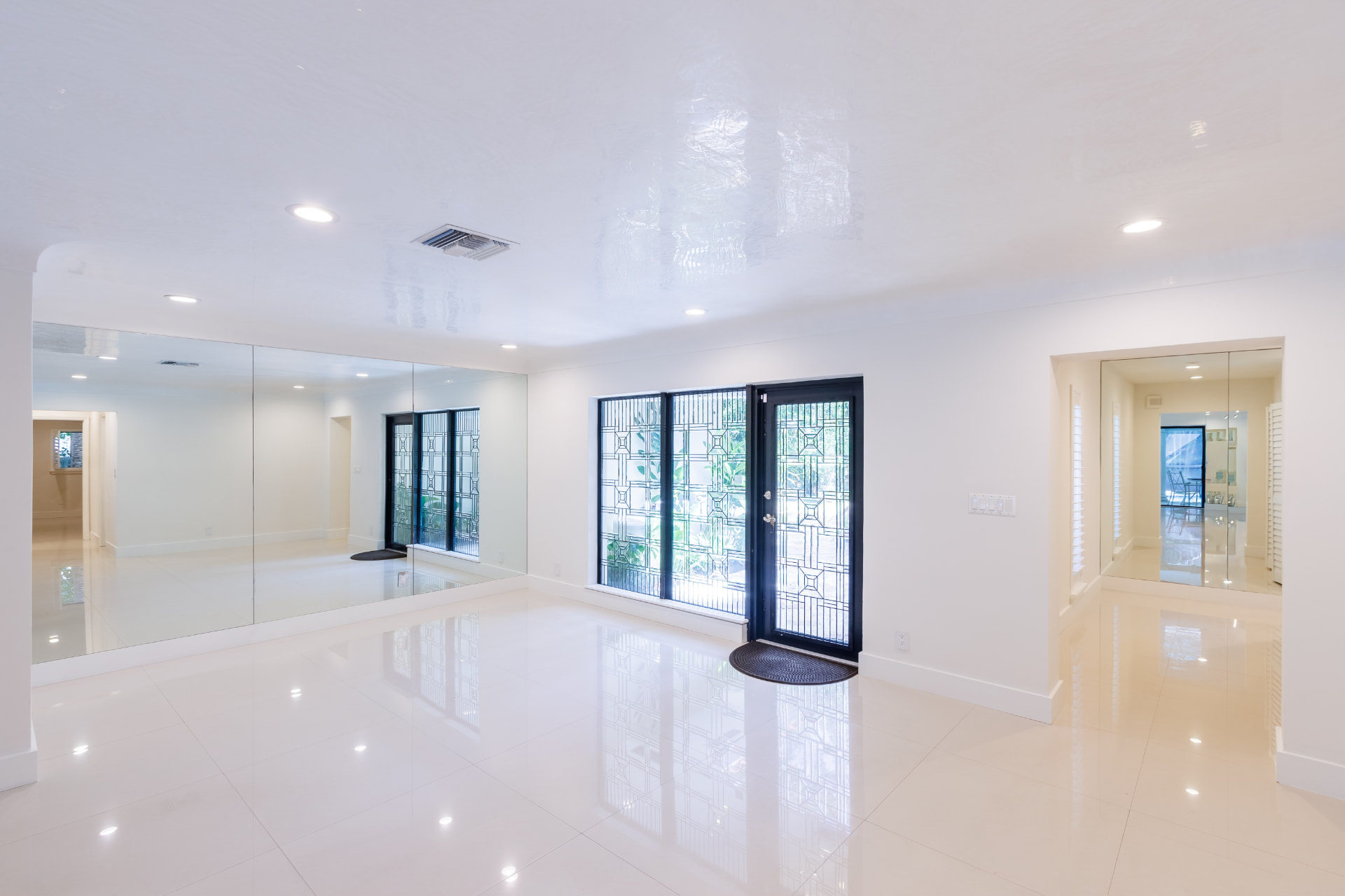 Entry and living room with leaded-glass front door and mirrored walls