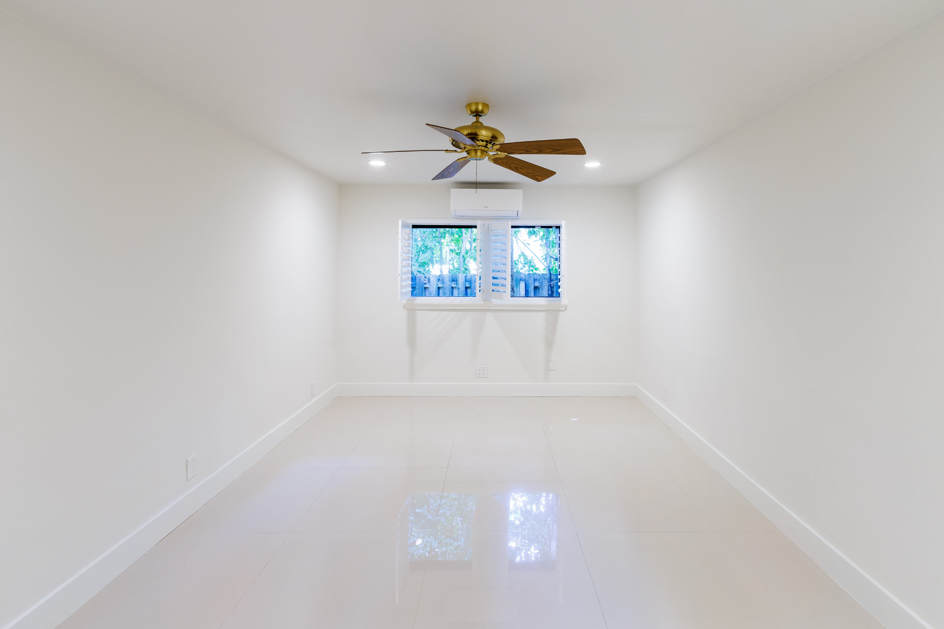 Guest bedroom with brass ceiling fan and garden views