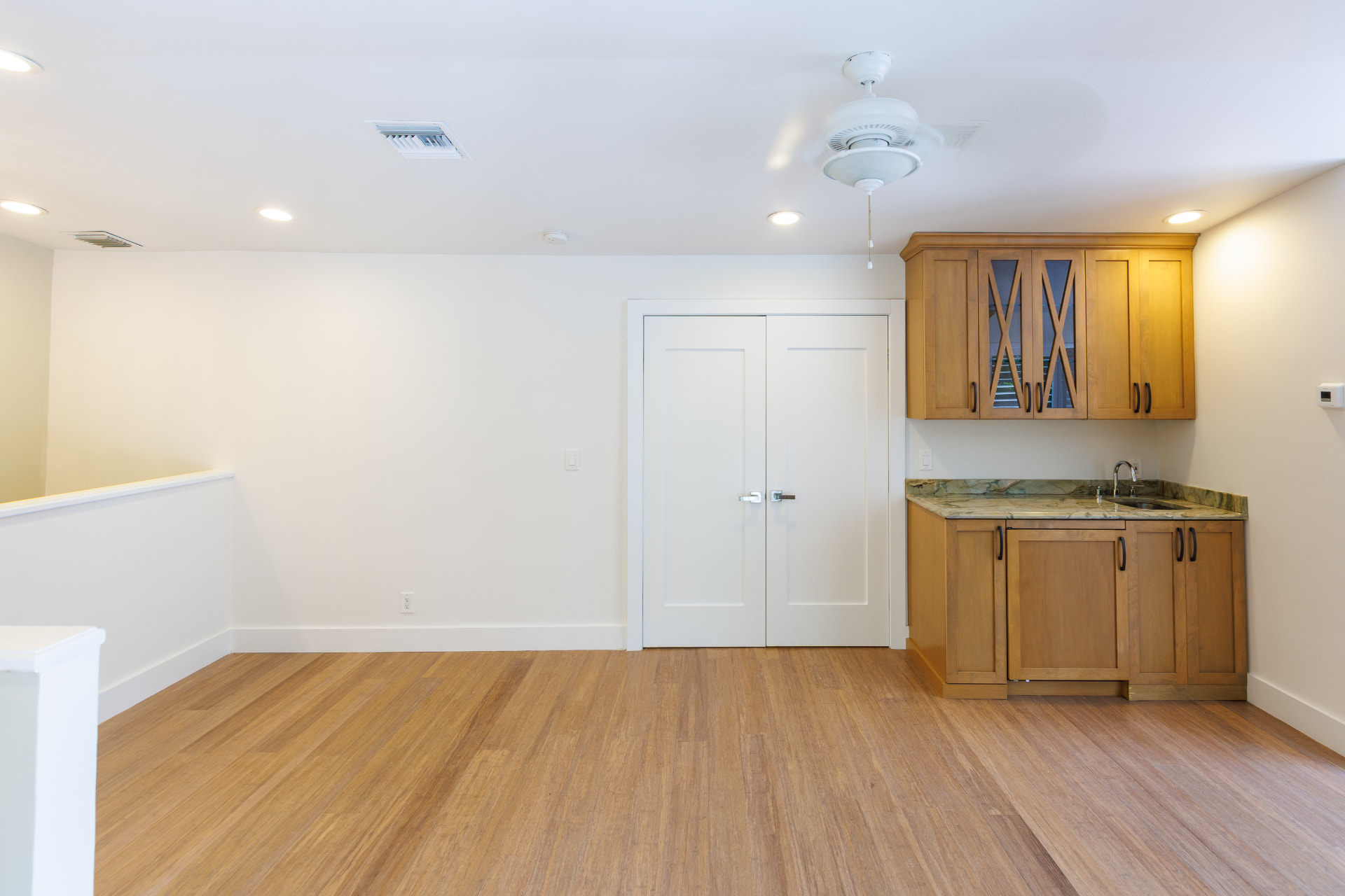 Upstairs room with wet bar cabinetry and wood floors