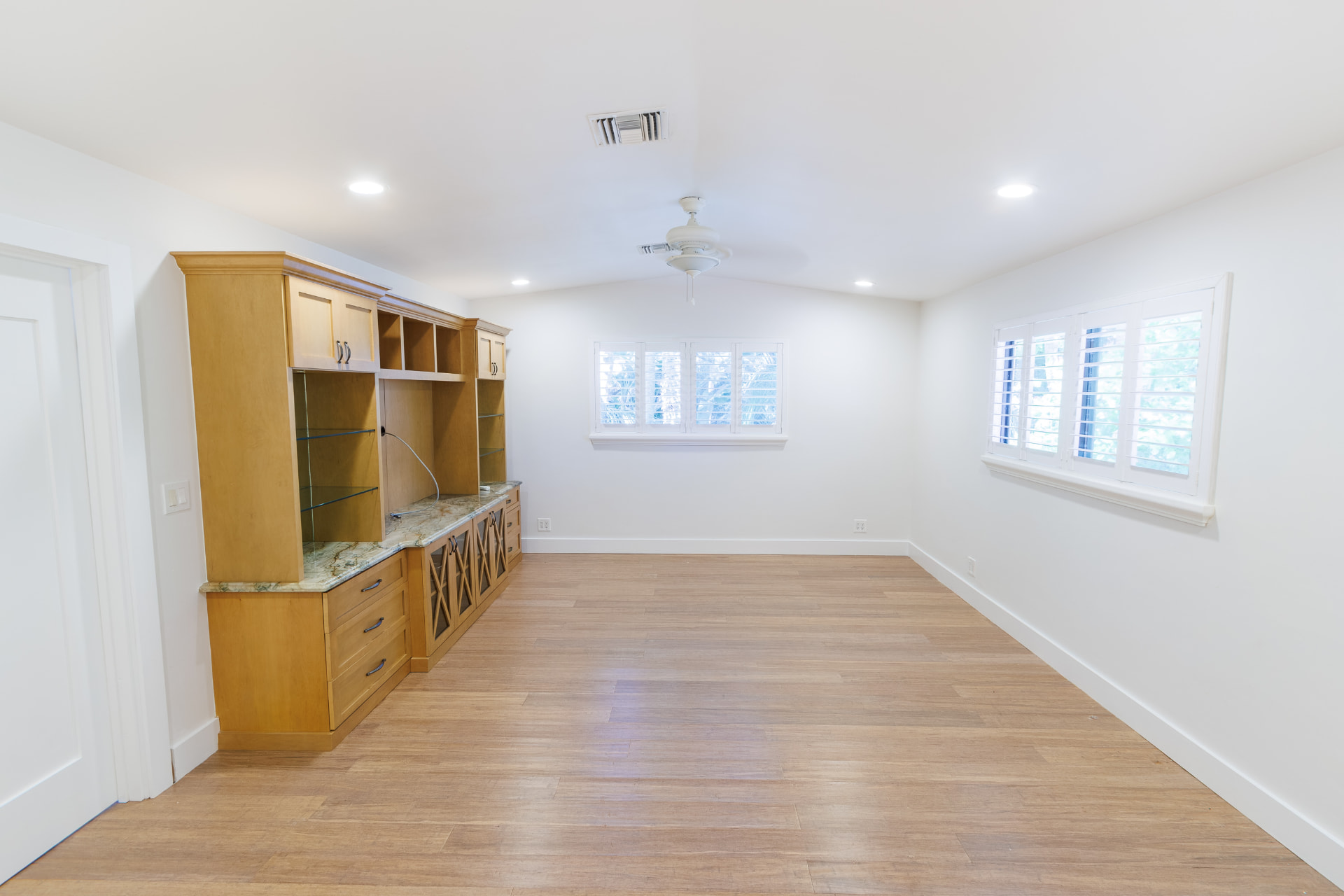 Media room with built-in entertainment wall and wood floors