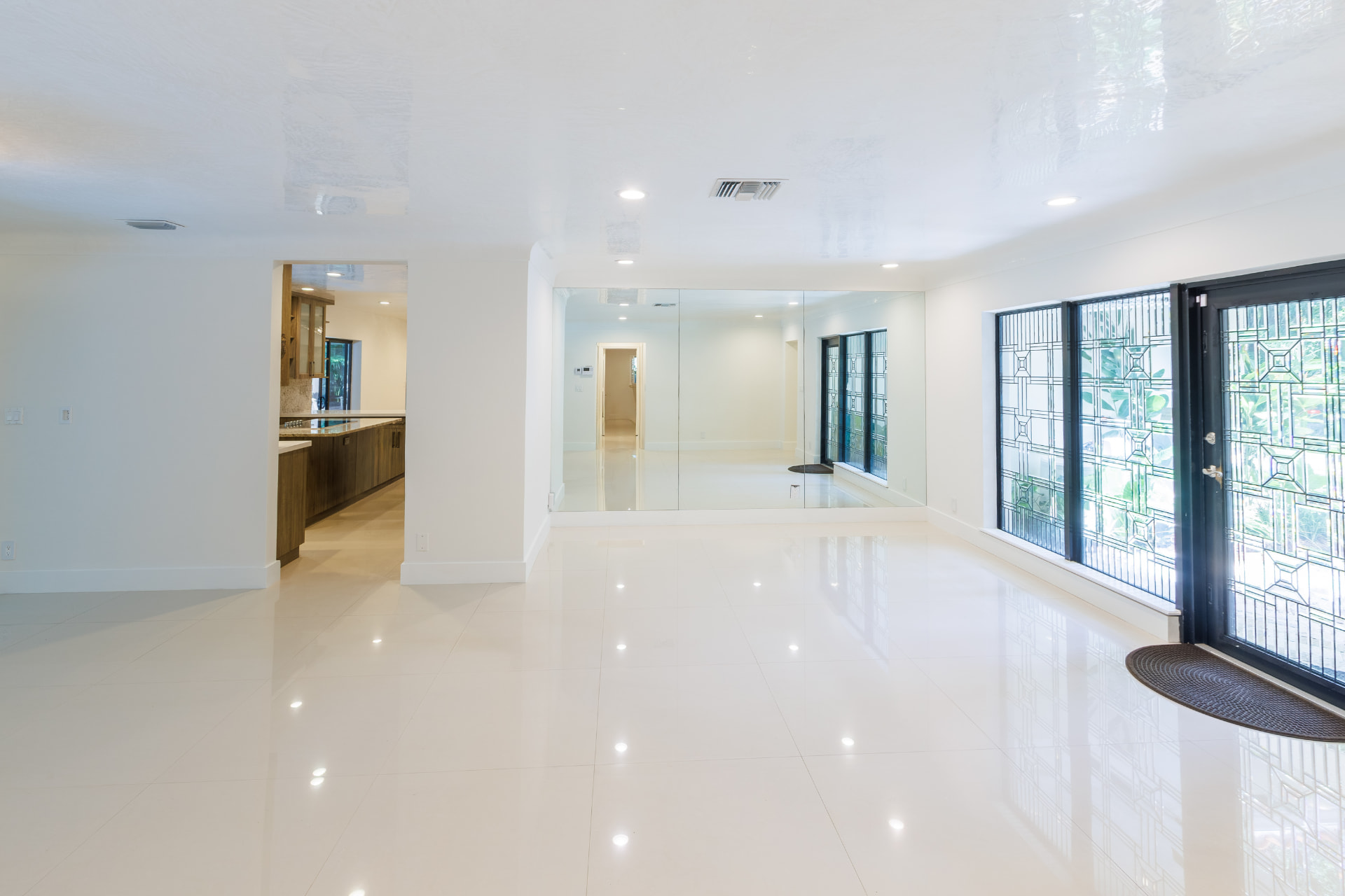 Living room with mirrored accent wall opening to the kitchen