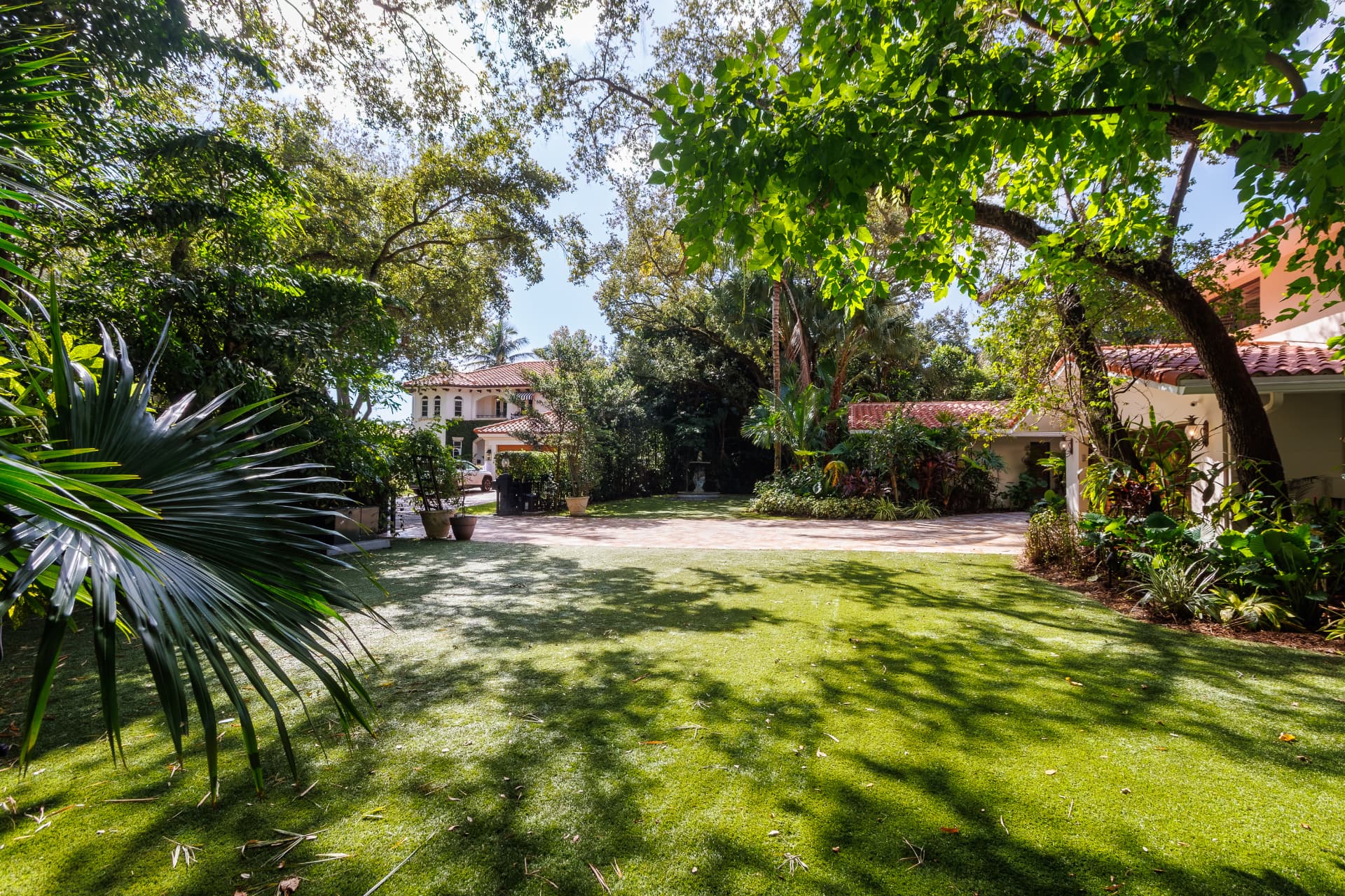 Garden and motor court framed by palms and canopy